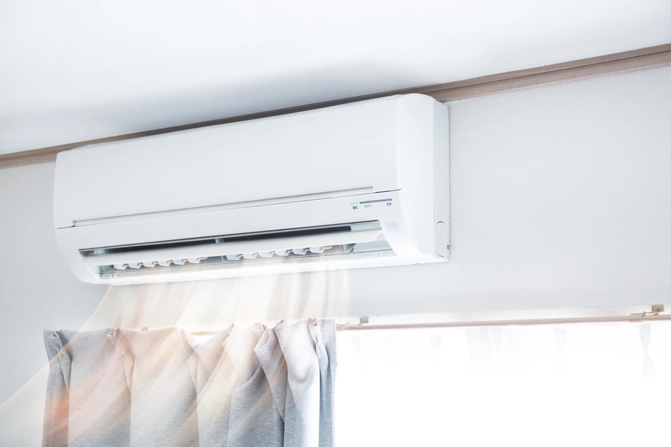 Intérieur résidentiel avec climatiseur mural blanc monté au plafond en fonctionnement, diffusant de l'air frais visible par effet de brume