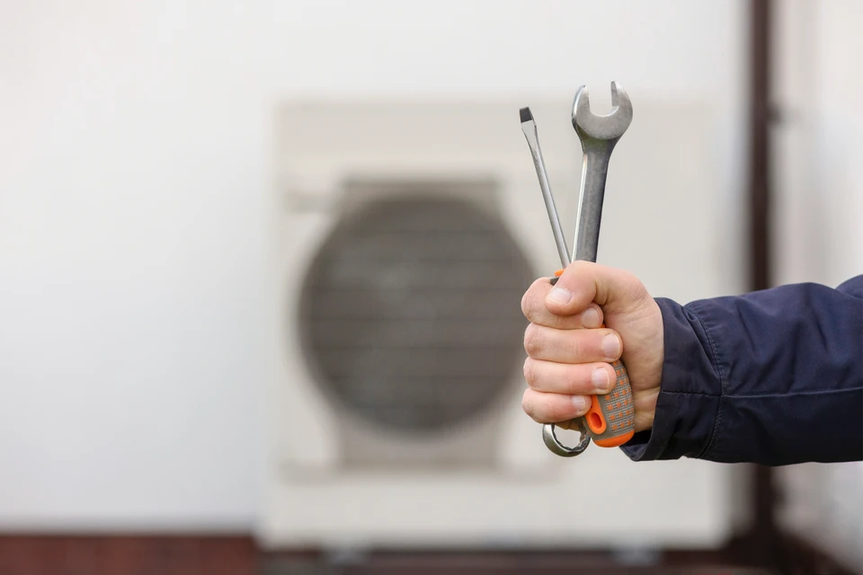 Un technicien travaillant sur la climatisation ou la pompe à chaleur d'une unité extérieure