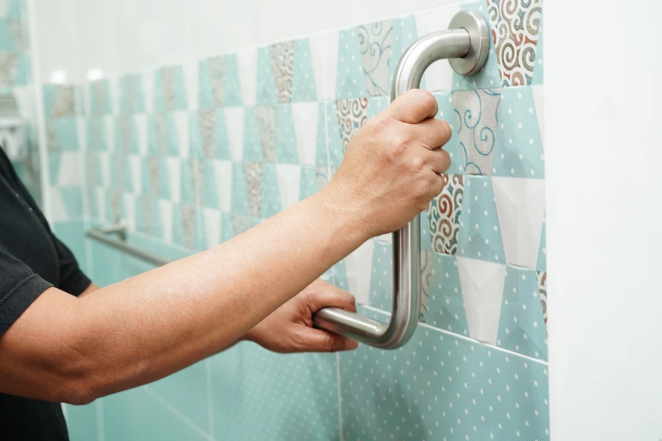Plombier en combinaison bleue inspecte robinetterie de baignoire blanche avec tablette rouge dans salle de bain carrelée blanc