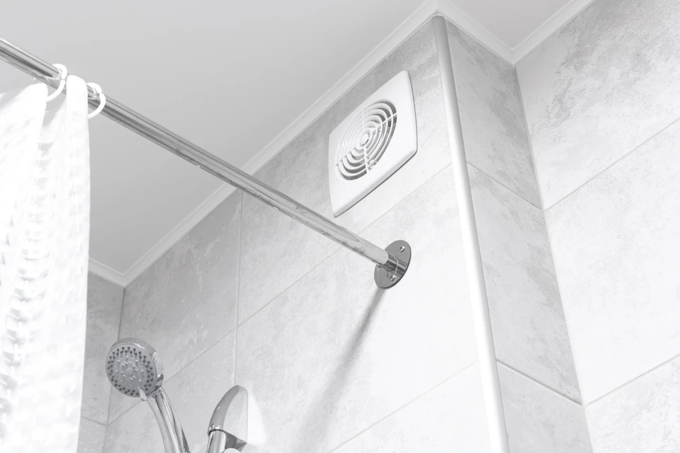 Photographie intérieure d'un technicien en tenue professionnelle effectuant l'installation ou l'inspection d'une unité de ventilation mécanique contrôlée fixée au plafond ou à un mur dans une maison en rénovation. Le technicien doit vérifier ou manipuler l'équipement. L'environnement montrera une pièce de vie ou une chambre avec éléments de rénovation, apportant clarté sur le contexte résidentiel. La photo doit transmettre le professionnalisme et la technicité de la mise en place d'une VMC pour améliorer la qualité de l'air intérieur.